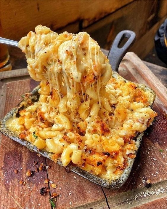 a spoon full of macaroni and cheese being lifted from a casserole dish