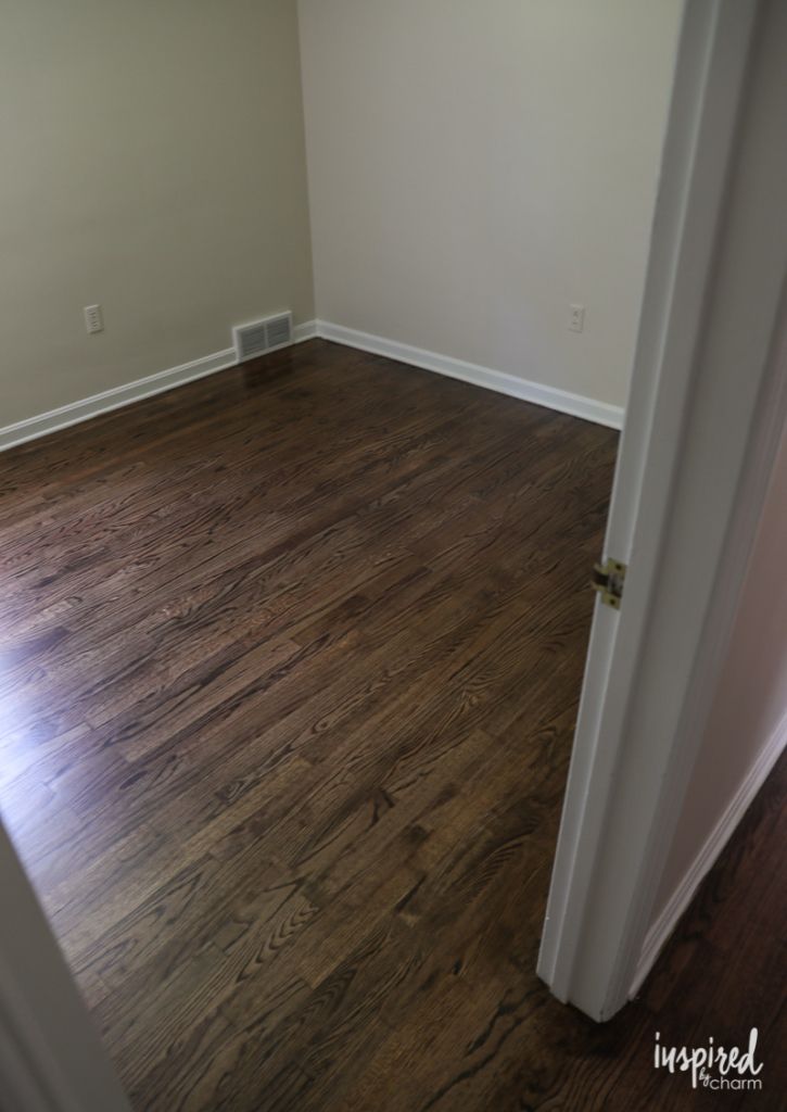 an empty room with hard wood flooring and white trim on the door way to another room