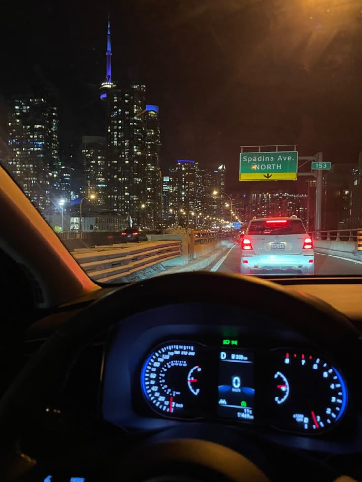 the dashboard of a car on a highway with city lights in the background at night