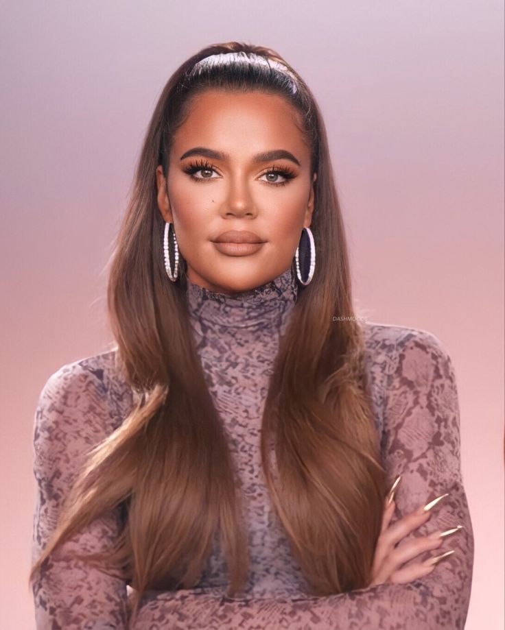 a woman with long brown hair and large hoop earrings on her head, standing in front of a pink background