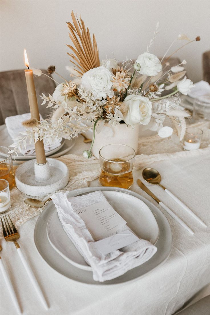 the table is set with white flowers and silverware