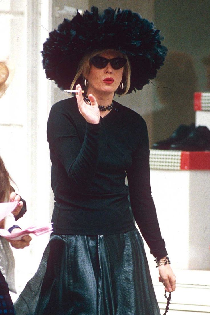 two women walking down the street with hats on their heads and one woman talking on her cell phone