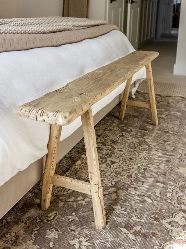 a wooden bench sitting on top of a bed next to a white bedspread