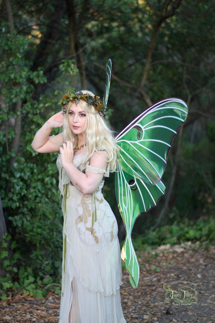 a woman dressed as a fairy holding a green butterfly on her shoulder and posing for the camera