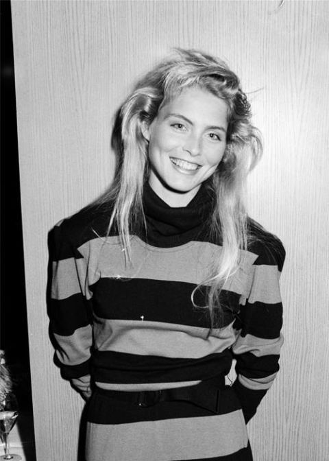 a black and white photo of a woman in a striped dress smiling at the camera