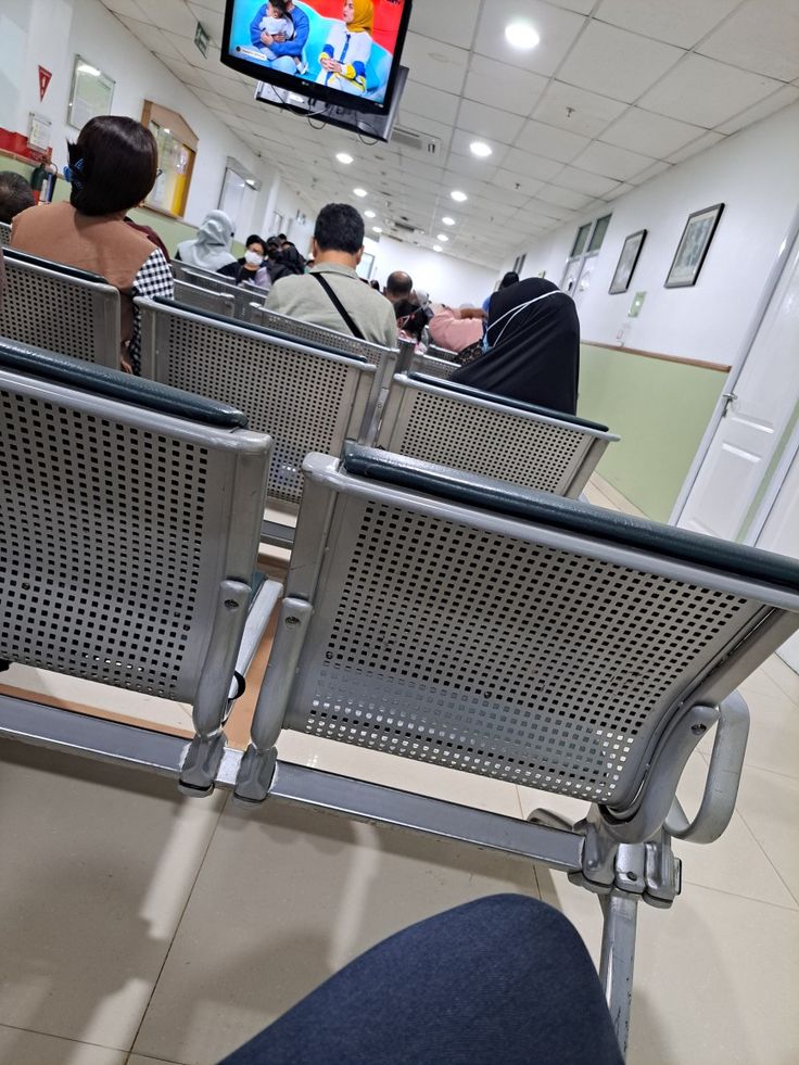 people are sitting in chairs watching television at an airport terminal with no one on the plane