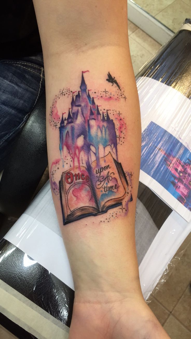 a person with a tattoo on their arm and an open book in the shape of a castle