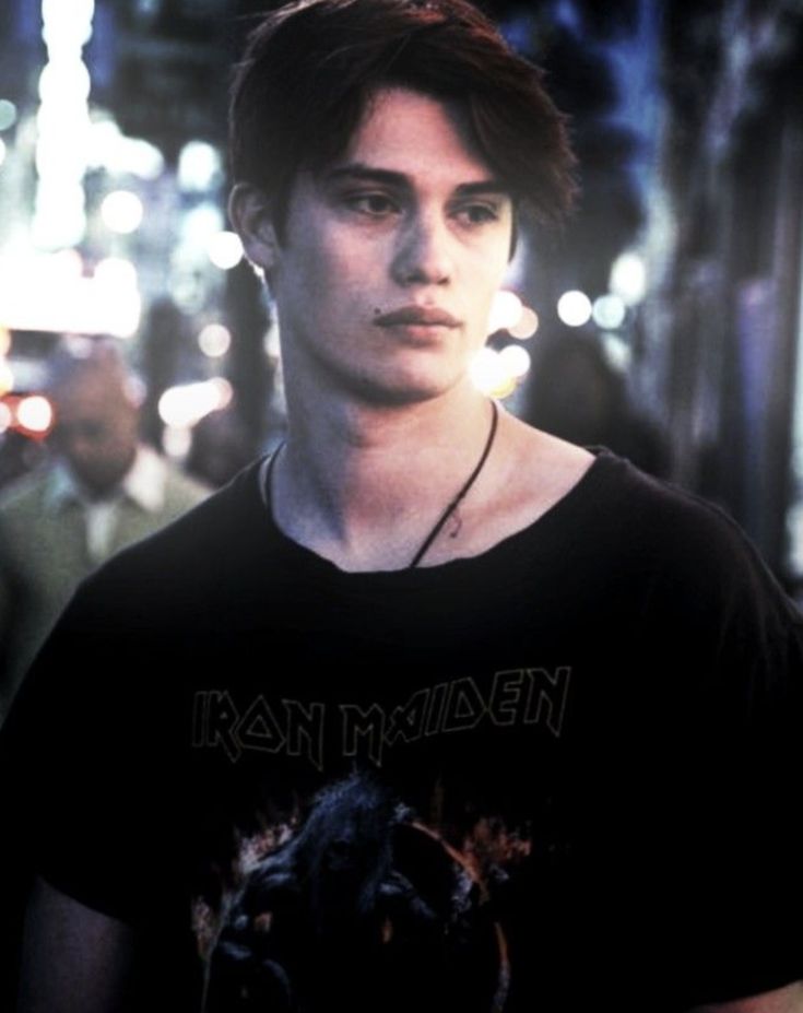 a young man standing in the middle of a street at night wearing a black shirt