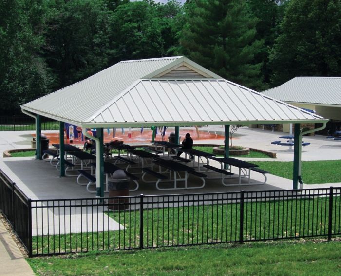 a pavilion with benches and tables in the middle of a grassy area next to trees