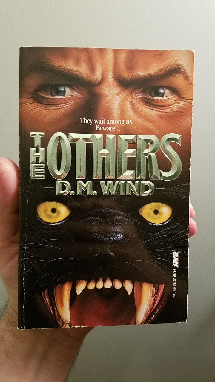 a person holding up a book with an image of a cat's face on it