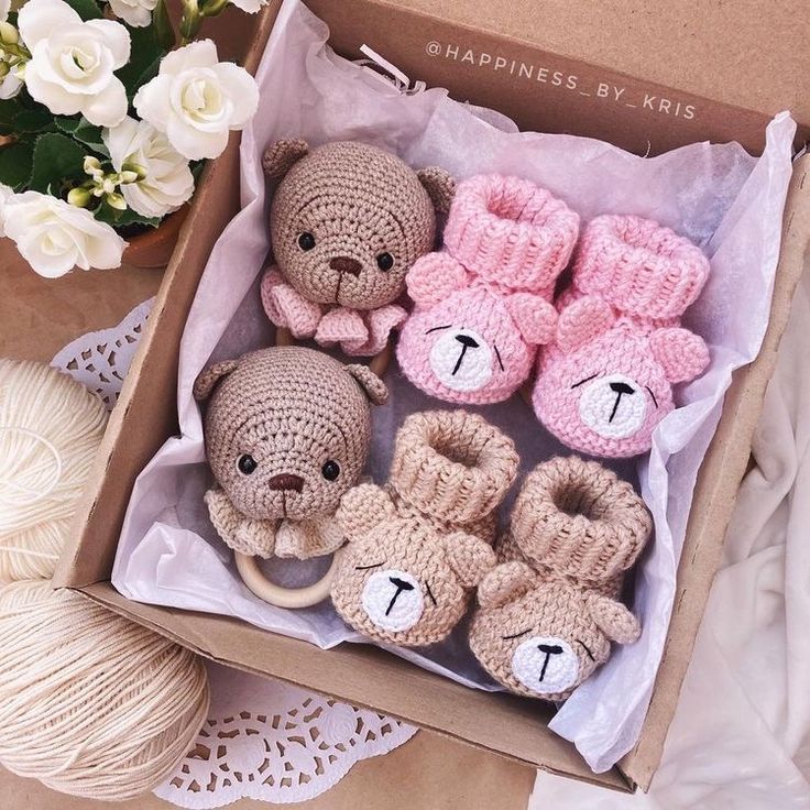 a box filled with crocheted teddy bears and slippers next to a ball of yarn