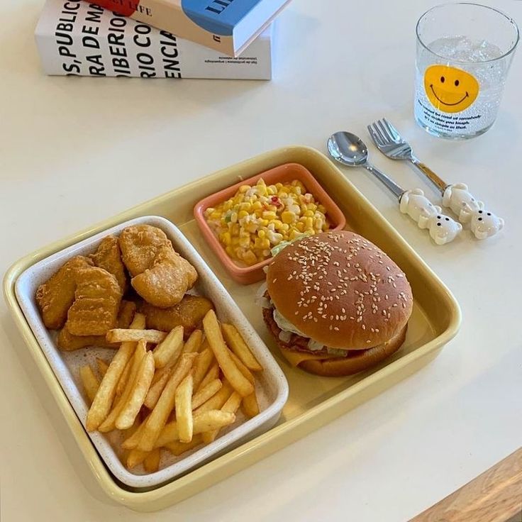 a lunch tray with chicken, french fries and coleslaw on it next to a book