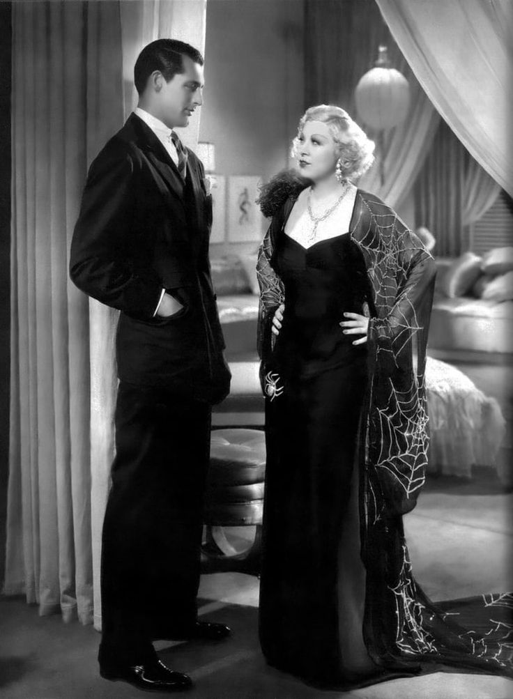 an old black and white photo of a man and woman in formal wear standing next to each other