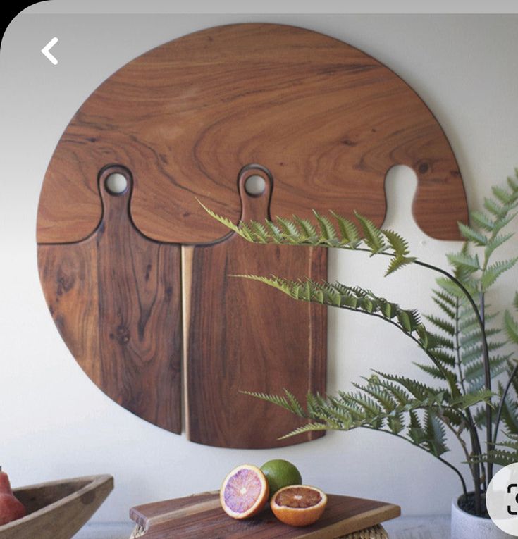 a wooden cutting board sitting on top of a table next to a potted plant