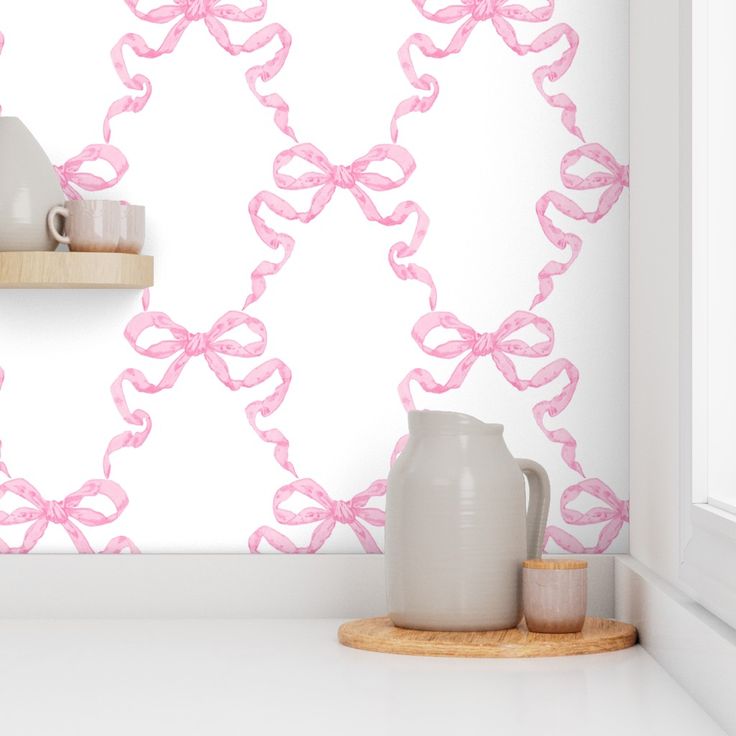 a white vase sitting on top of a counter next to a wall with pink bows