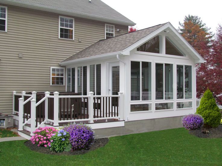 a white house with lots of windows and flowers in the front yard