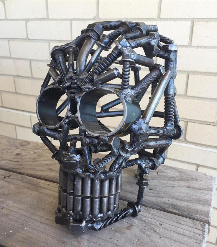 a sculpture made out of metal parts sitting on top of a wooden table