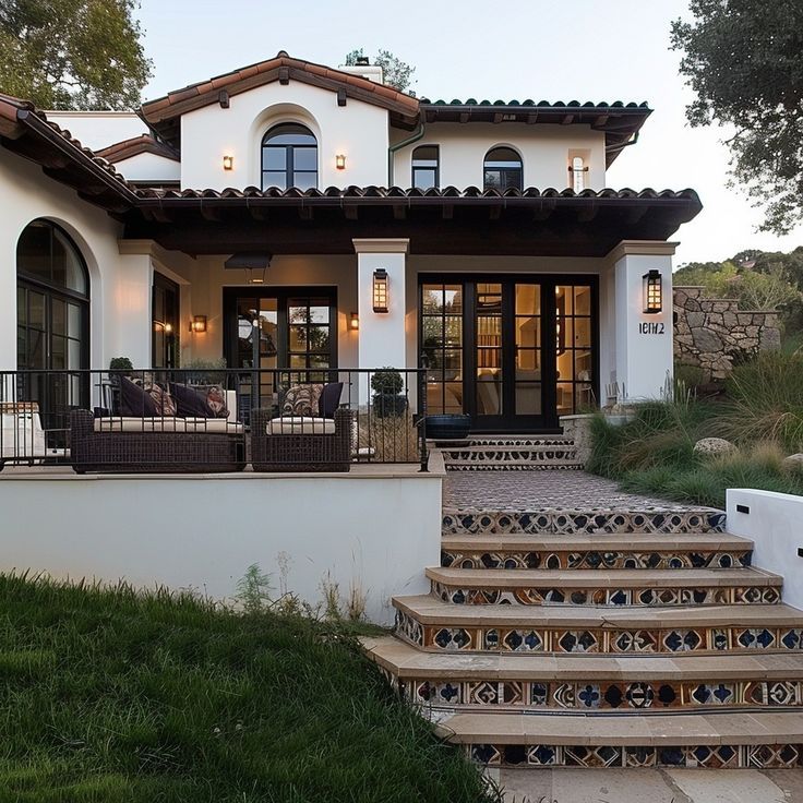 a house with steps leading up to the front door and covered patio area on top of it