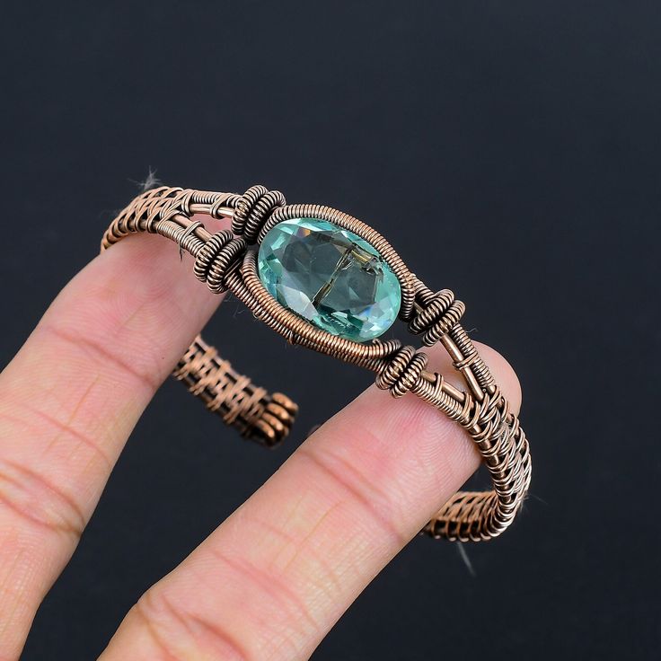 a hand holding a ring with a blue stone in it's center and an intricate design around the band