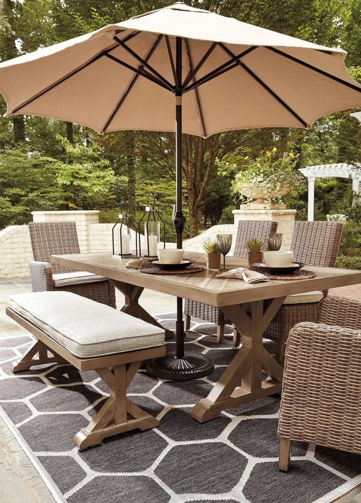 an outdoor dining table with chairs and umbrella