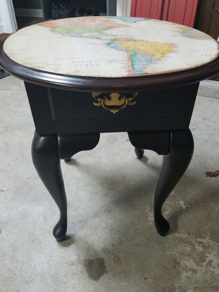 an old world map on top of a black table with gold trimmings and knobs