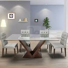 a glass dining table with white chairs and a potted plant in the corner next to it