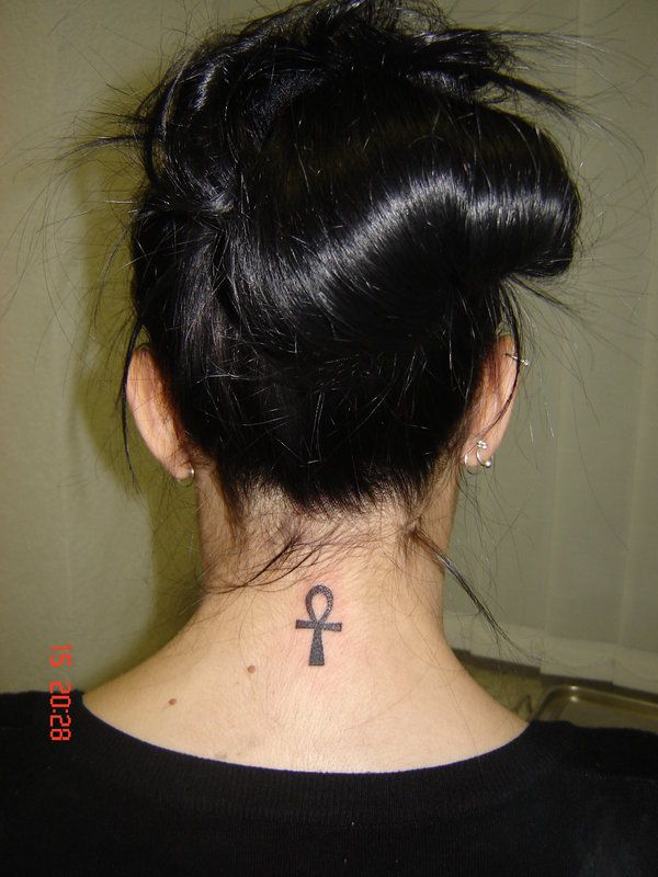 the back of a woman's neck with an anchor tattoo on her left side