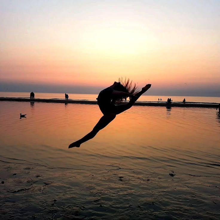 a person jumping into the water at sunset