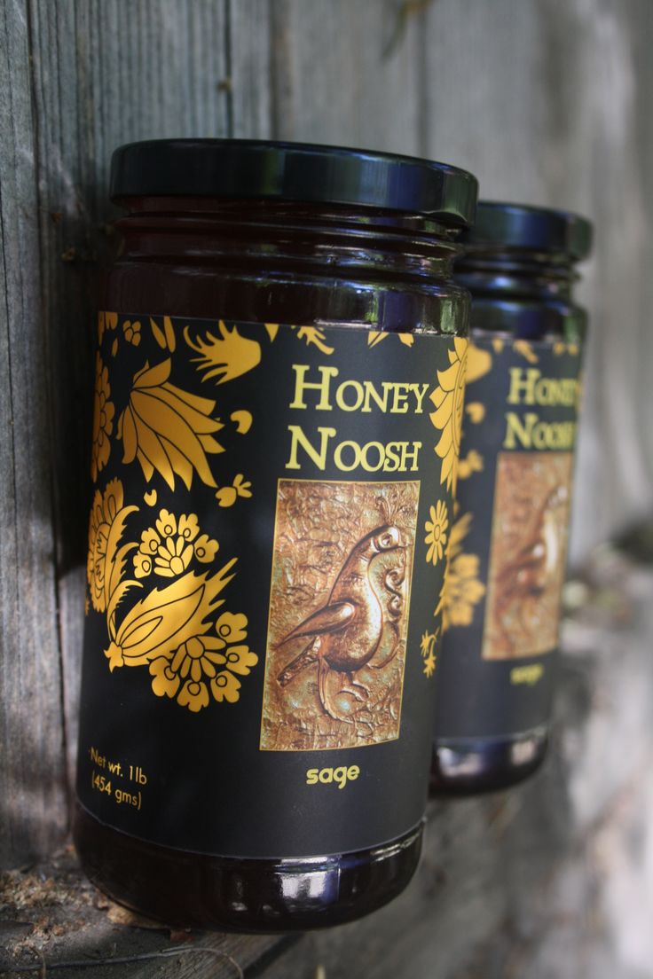 three jars of honey sitting on top of a wooden fence next to each other,