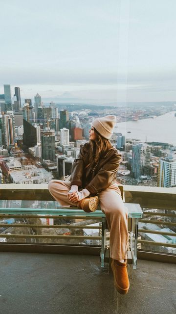 a woman sitting on top of a metal bench in front of a cityscape