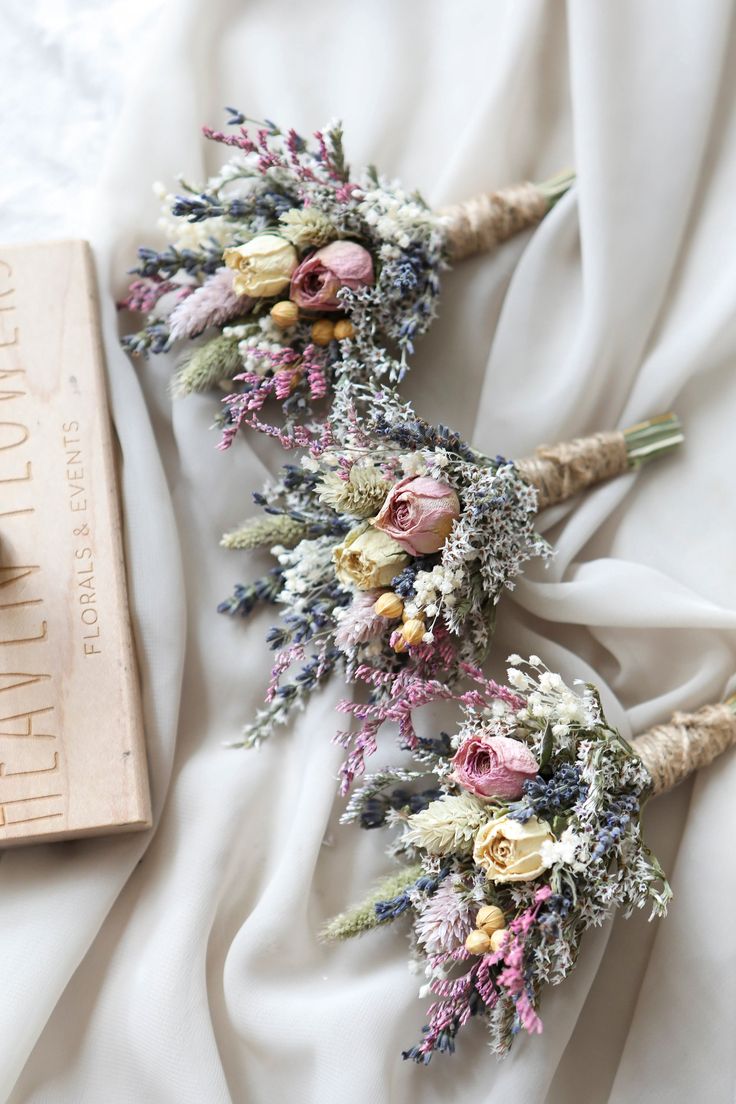 three bouquets of flowers are laid out on a white sheet with a book nearby