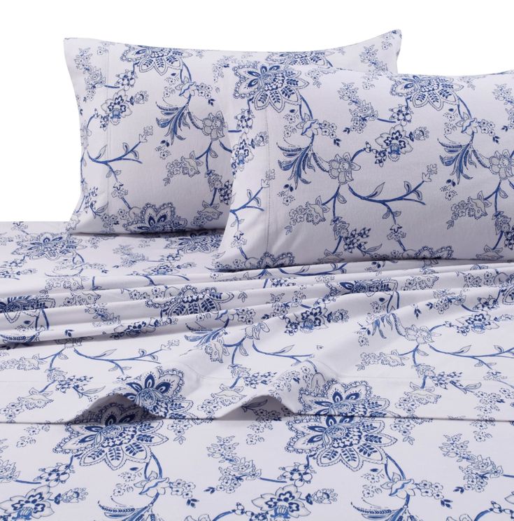 a bed with blue and white sheets and pillows on top of it, along with two pillow cases