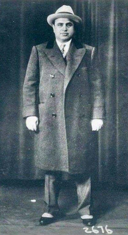 an old photo of a man in a coat and hat