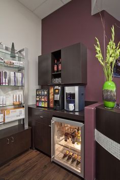 an open refrigerator in a small room with shelves on the wall and a vase filled with flowers