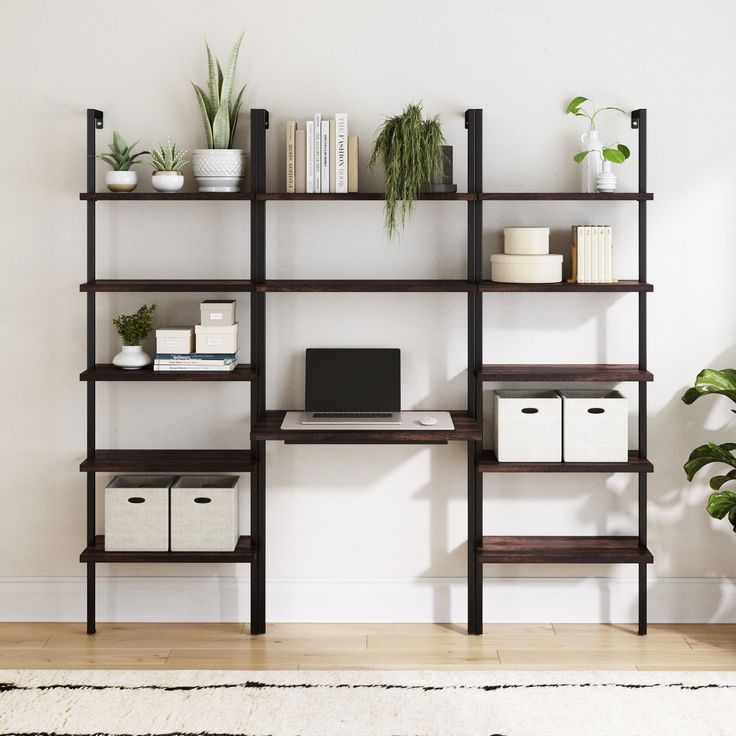 a computer desk sitting on top of a wooden shelf next to a potted plant