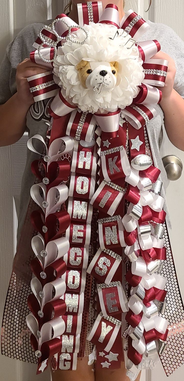 a person holding a teddy bear with ribbon around it's neck and wearing a santa hat