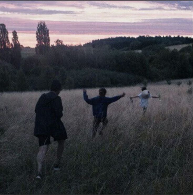 three people standing in the middle of a field with their arms spread out and lights shining on them