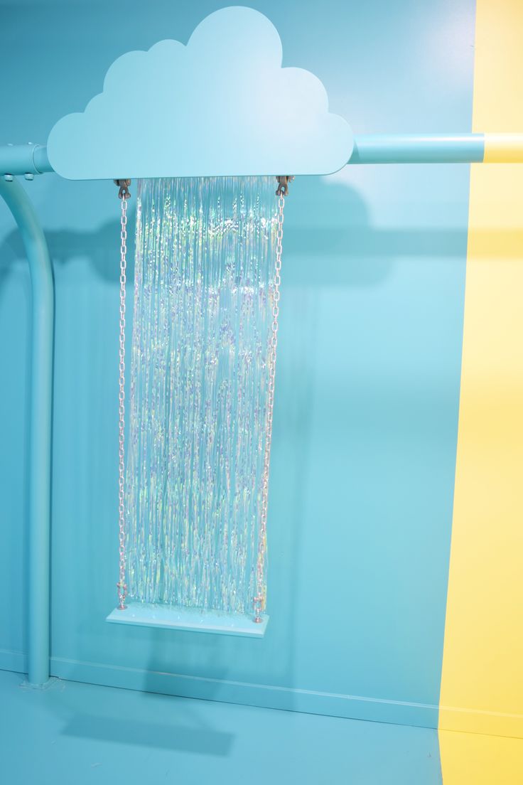 a blue wall with a window and rain curtain hanging from it's side in front of a cloud