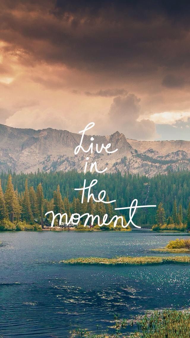 the words live in the moment are written over a lake with mountains in the background