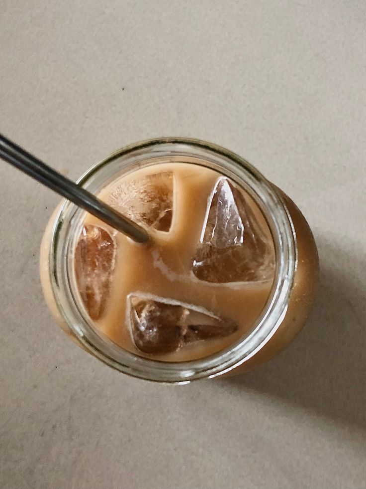 an iced drink with ice cubes and a straw in a glass on a table