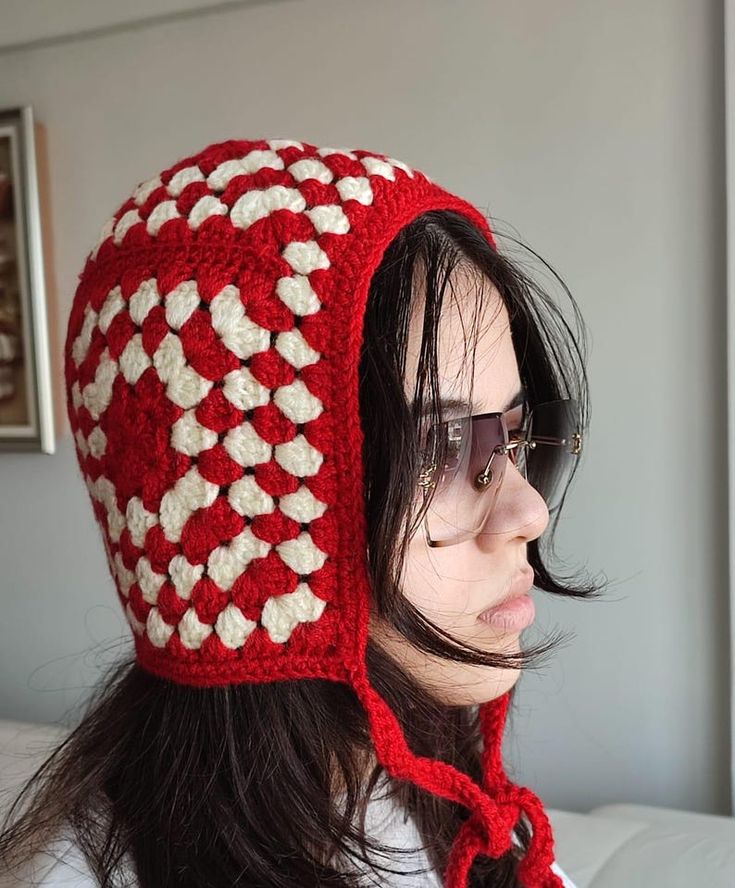 a woman wearing a red and white crocheted hat with hearts on the side