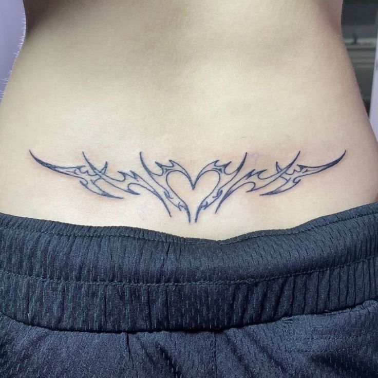 a woman's lower back tattoo with birds in the shape of a heart on her stomach