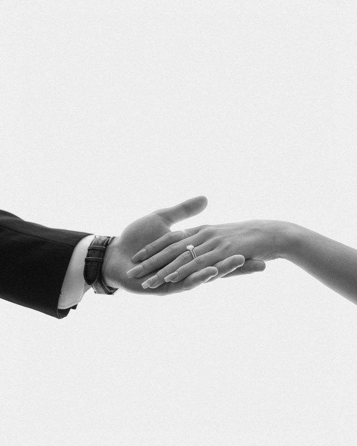 two people reaching out their hands to each other in black and white photo with sky background