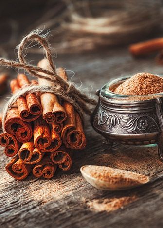 cinnamon sticks are next to an old metal container with cinnamons in it on a wooden table