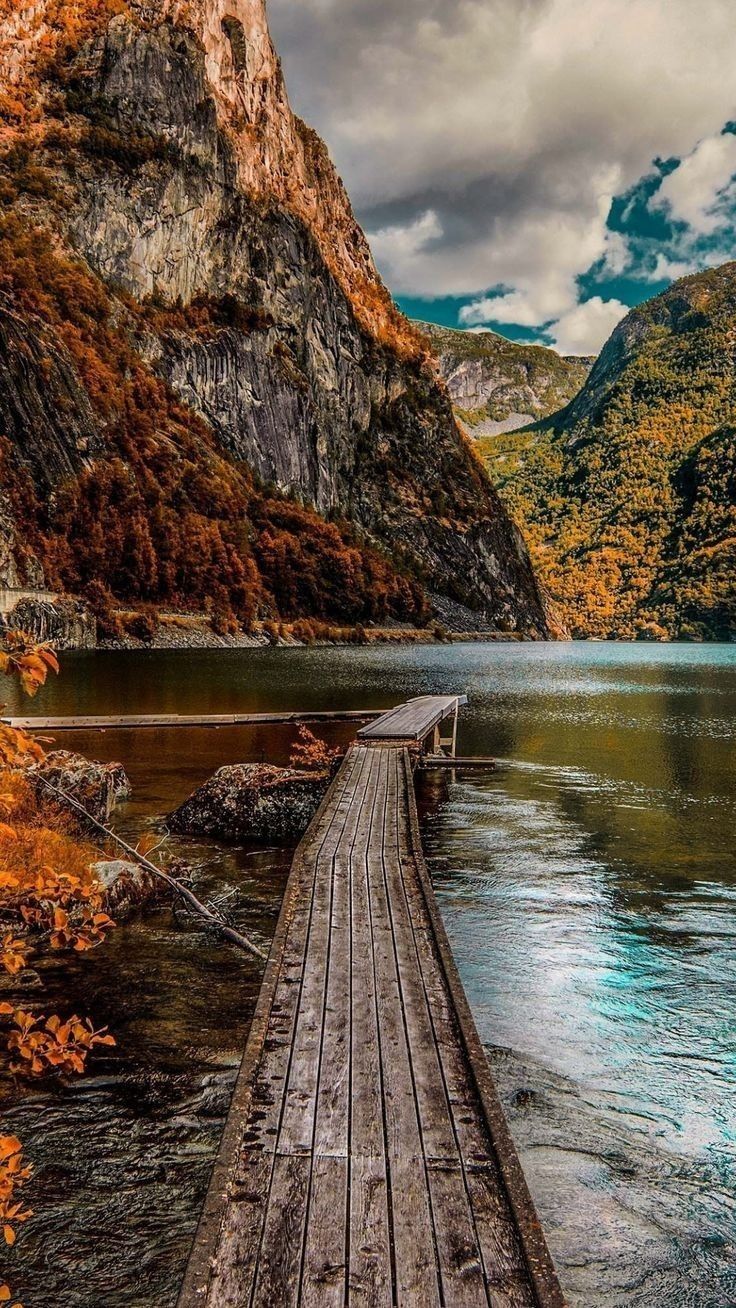 a wooden dock sitting on top of a lake surrounded by mountains