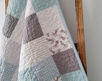 a blue and white quilt hanging from a wooden chair in front of a wall mounted clock