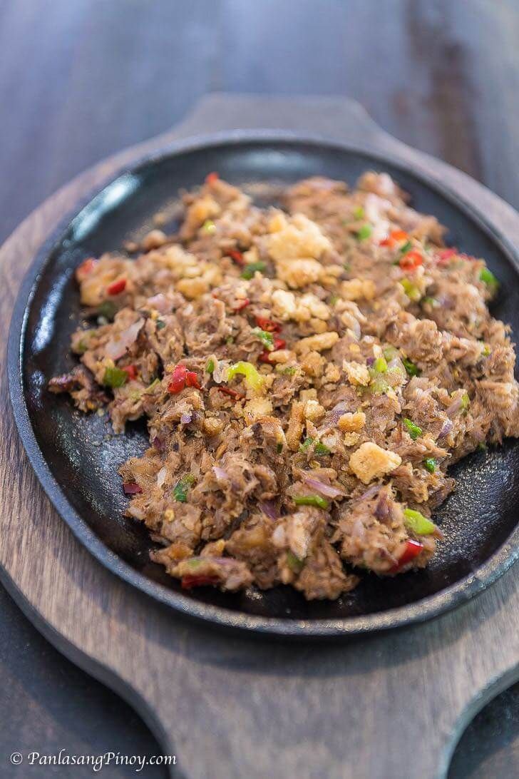 a pan filled with meat and vegetables on top of a wooden table