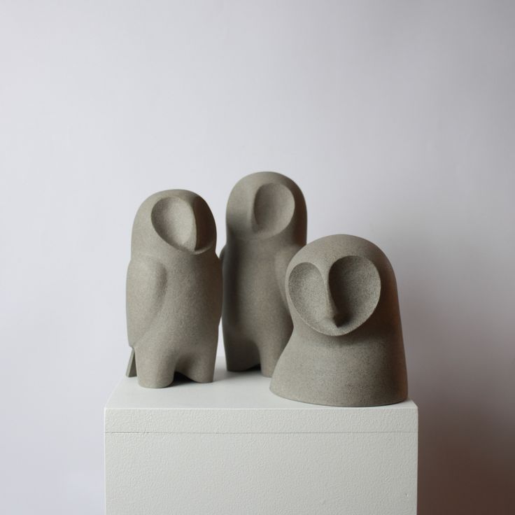 two small sculptures sitting on top of a white block