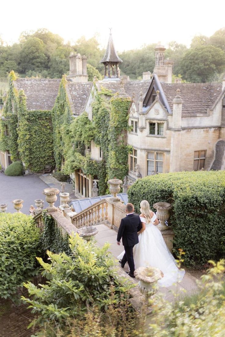 a bride and groom walking up the stairs to their wedding venue in front of an old castle