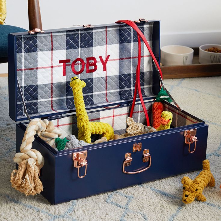 an open suitcase with toys in it sitting on the floor next to a stuffed giraffe